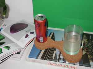 A chunky curved coaster with space for two drinks on top of a coffee table book.